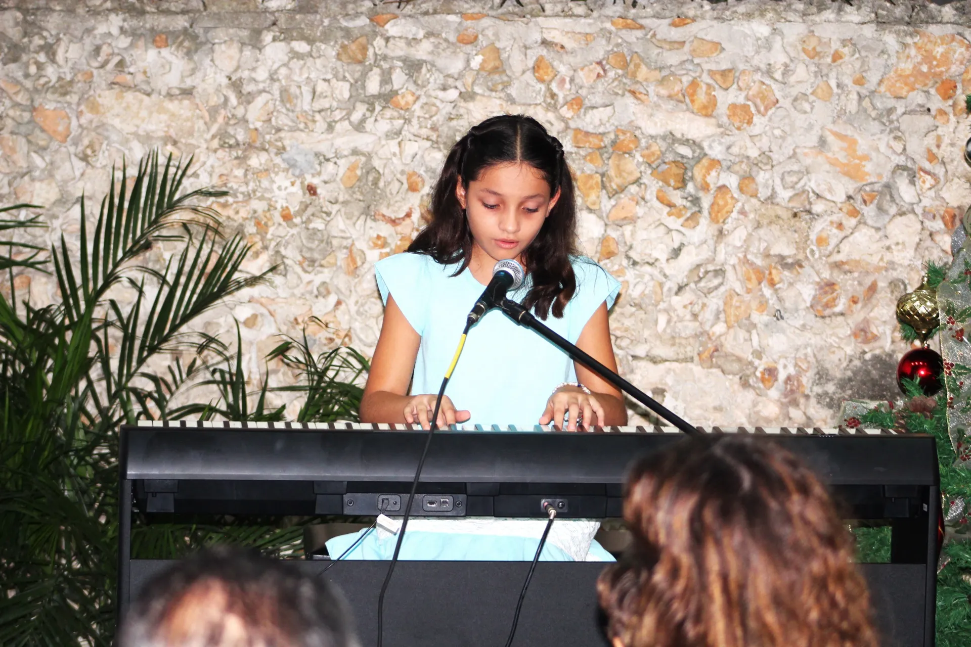 Una alumna canta frente al micrófono mientras toca el teclado.