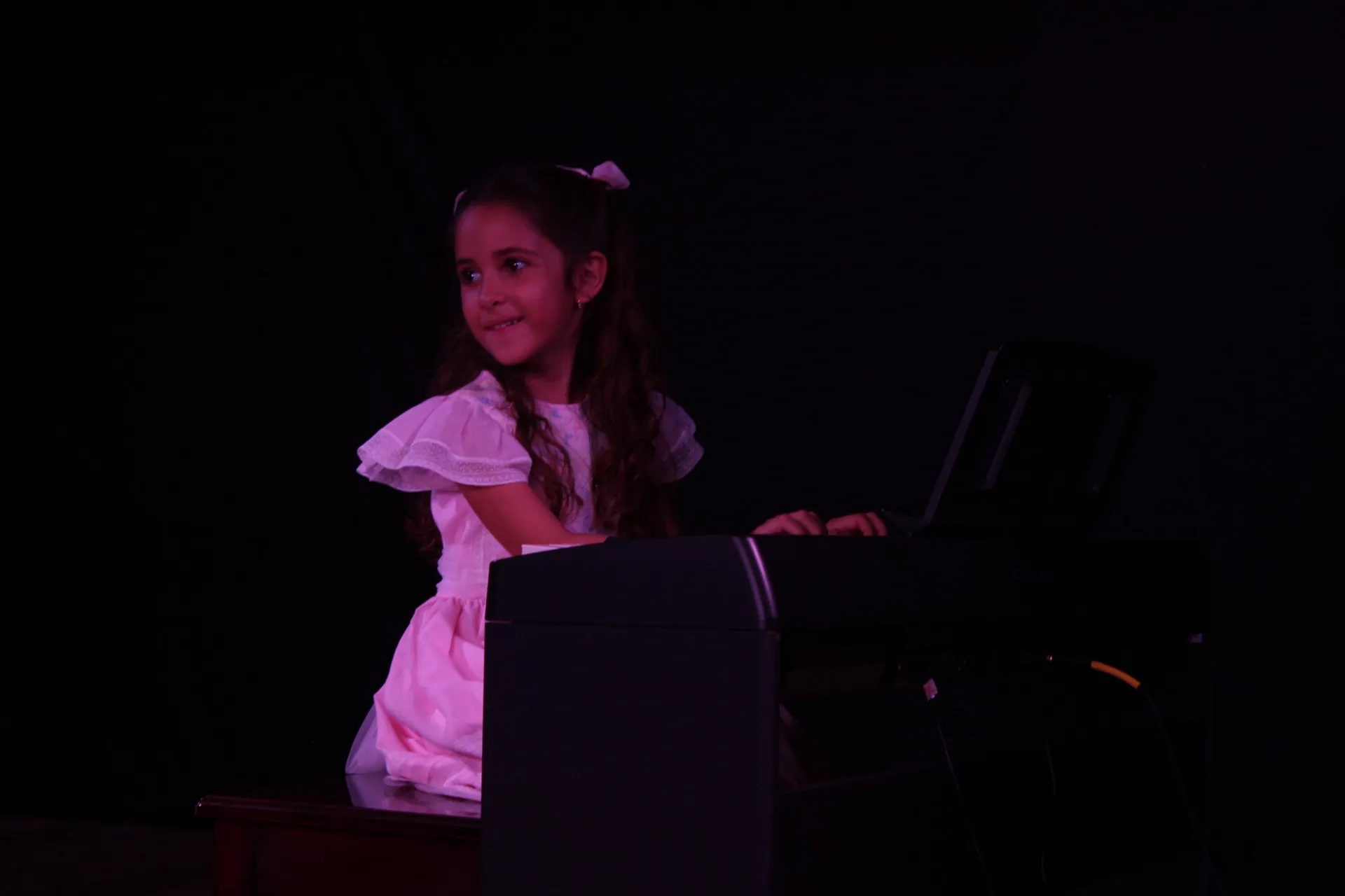 Una niña sonríe al público desde el piano durante un recital.